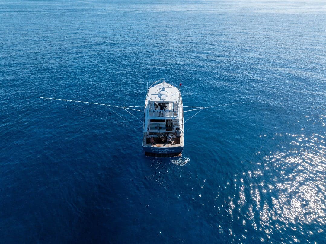 Sportfish convertible running offshore at sunset with outriggers set
